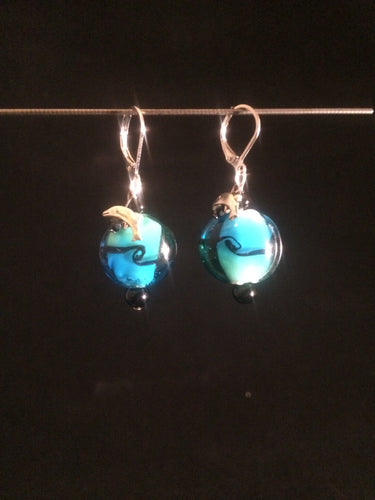 Leverback earrings made with a blue blown glass bead and adorned with a plated metal charm of either a fish, dolphin, or a shell.  Faceted and round glass beads are added for accent.