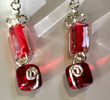 Load image into Gallery viewer, Red glass beads form geometric patterns in rectangles and cylinders, with swirly silver wire looped in between on these leverback silver earrings.
