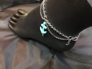 A delicate stainless steel chain swags from a main stainless steel chain, providing a scalloped design to this surf-resistant anklet. Reassembled turquoise anchor charms accent the nodes of the scallop.