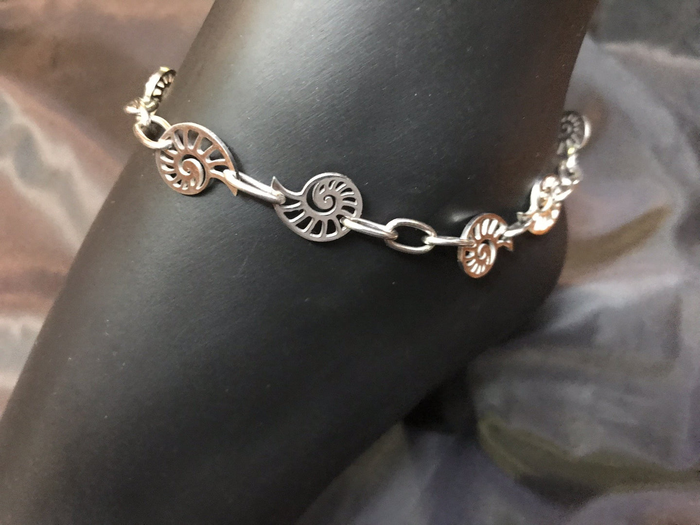 Delicate stainless steel nautilus charms form links in the chain in this rust-resistant anklet that can stay with you throughout all your adventures.