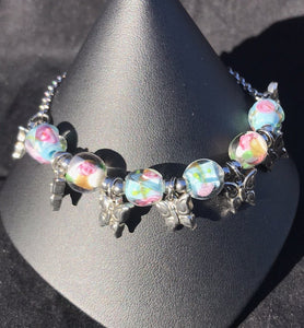 Made from high grade 304 stainless steel, this sturdy corrosion-resistant bracelet features blown glass beads depicting roses, accented by stainless steel butterfly charms between each of the beads.