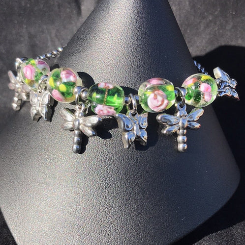 Made from high grade 304 stainless steel, this sturdy corrosion-resistant bracelet features blown glass beads depicting flowers, accented by stainless steel dragonfly charms between the beads.