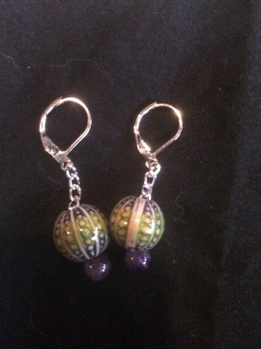 A pair of purple sea urchin mood beads that change color with temperature sits on silver plated chain below silver plated brass leverbacks.