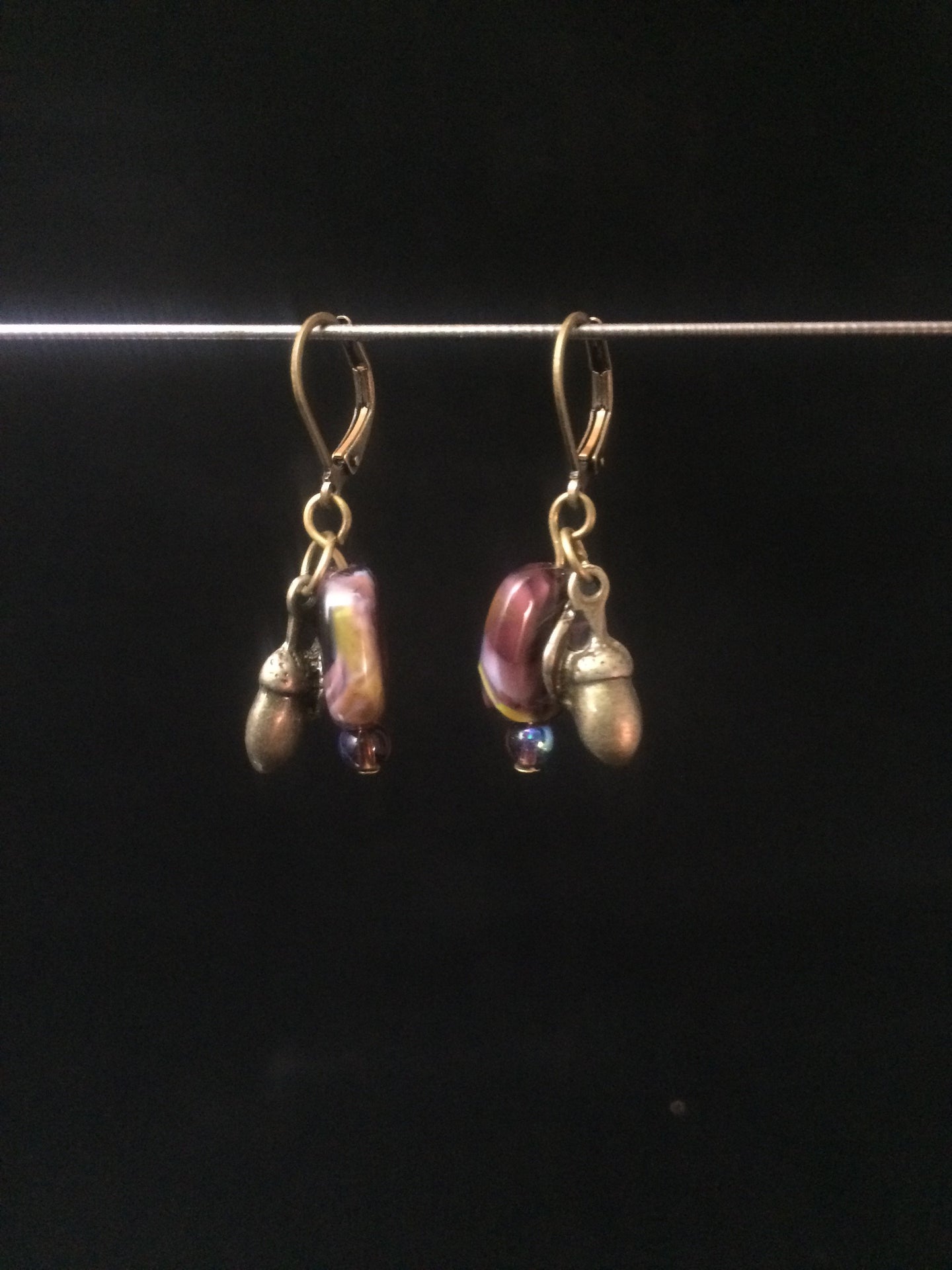 Leverback Earrings made from purple blown glass beads that have swirls and metal acorn charms.åÊ Round glass pearls are added for accent.