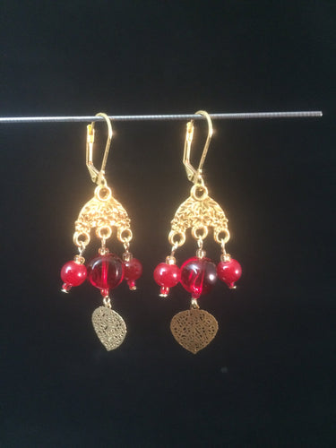 Leverback chandelier earrings adorned with red glass beads and a metal leaf charm.