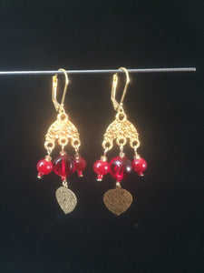 Leverback chandelier earrings adorned with red glass beads and a metal leaf charm.