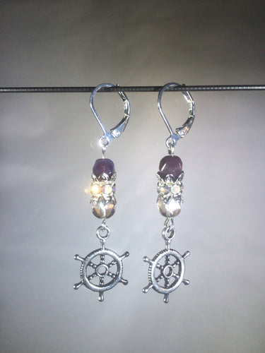 Leverback earrings with metal ship's wheel charms, purple colored and faceted glass beads, and a faceted crystal cluster.