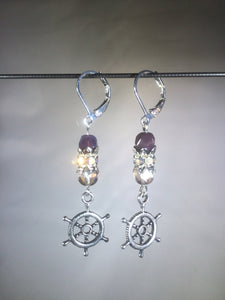 Leverback earrings with metal ship's wheel charms, purple colored and faceted glass beads, and a faceted crystal cluster.