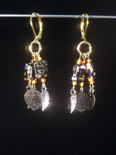These chandelier-styleåÊleverbackåÊearrings featureåÊ10mm square black millefiore beads with shiny leaf charms dangling below, for a total dangle length of about 1.5