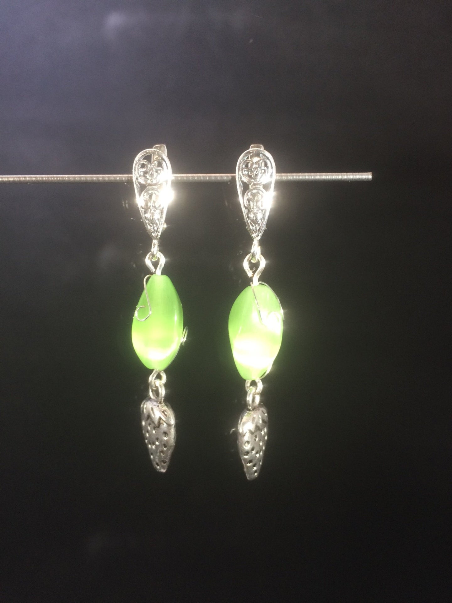 Tiny metal strawberry charms dangle from chatoyant green glass beads below silver plated brass leverbacks in these 1.5