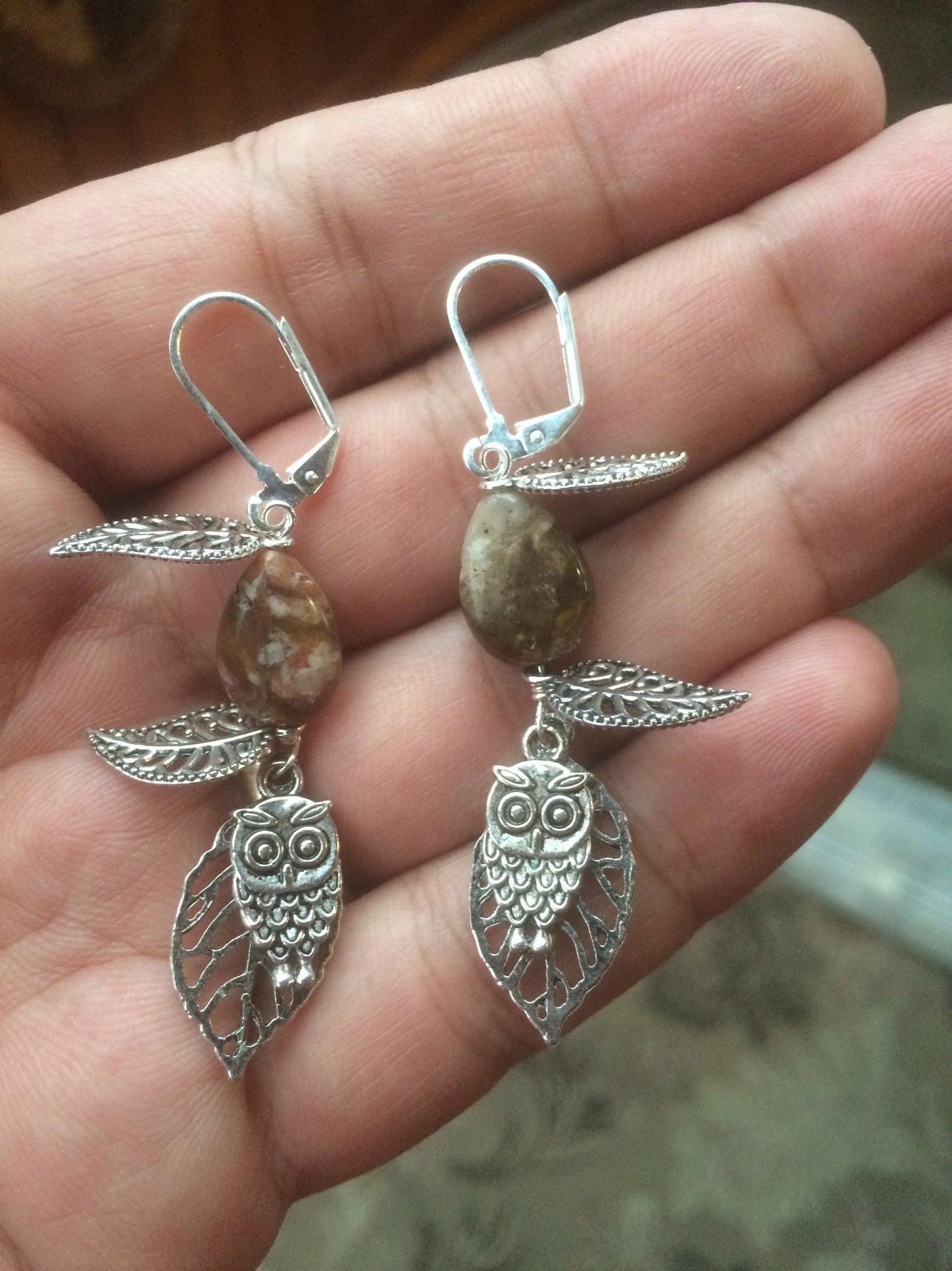 These earrings feature a metal owl dangling below falling metal leaves. This forms a matching set with necklace 1NCK0029.