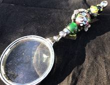 Load image into Gallery viewer, Tiny blown glass frogs appear to be climbing toward a central flowery blown glass bead, accented by viney rose charms, on the handle of this magnifying glass.