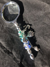 Load image into Gallery viewer, An anchor charm fixes the location conjured up by the sea life charms and dazzling blue-green cut and blown glass beads on the handle of this magnifying glass.