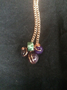 Three amethyst beads surround a green and white agate bead in a design meant to be evocative of a cluster of grapes, with the swirling copper wire wrap evoking images of the vine. The pendant is set on a 22" copper-plated steel chain, with a copper-plated steel circular spring clasp.