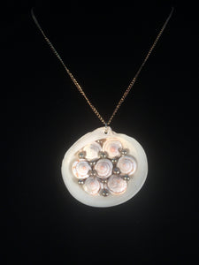 The pendant is made from a clam shell adorned with snail shell segments and green freshwater pearls, mounted on an 18" brass-plated steel chain. Forms a matching set when purchased with earrings 1EAR0122.