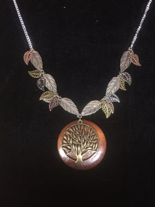 In this necklace, a wooden disk backs aåÊmetal tree of life pendant with metal leaves of different finishes and sizes surrounding it on the 18" plated steelåÊchain.
