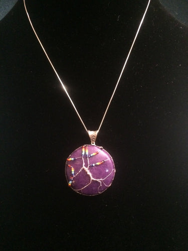 This tree of life uses the inclusive rainbow as the color theme made with glass seed beads on fine silver wire on a silver chain. The background is a cabochon of Mountain Jade (dolomite marble) which has been dyed to its color.