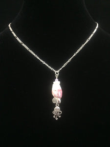 A barnacle sourced locally in St. Augustine Beach is accented by silver plated charms and glass beads, then mounted on a 16" silver tone steel chain.