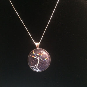 This tree of life uses the inclusive rainbow as the color theme made with glass seed beads on fine silver wire on a silver chain. The background is a 30mm cabochon of lab created sunstone in blue.