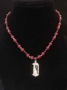 An hourlass charm adorns this 18" garnet and glass bead strand.