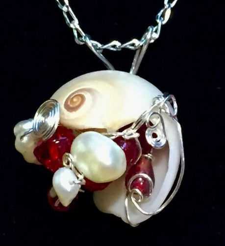Glass beads and freshwater pearls dazzle amongst fine silver wire swirls passing into and through an ethically beachcombed shell found on St. Augustine Beach, FL. The pendant is set onto a 16