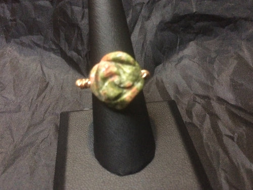 Tight copper coils provide the mounting for a 17mm flower carved from unakite in this copper wire-wrapped ring. Rings made by this wire wrapping method vary individually. This one is approxmately a size 9.5, but may fit a slightly larger finger depending on how snug a fit you prefer.