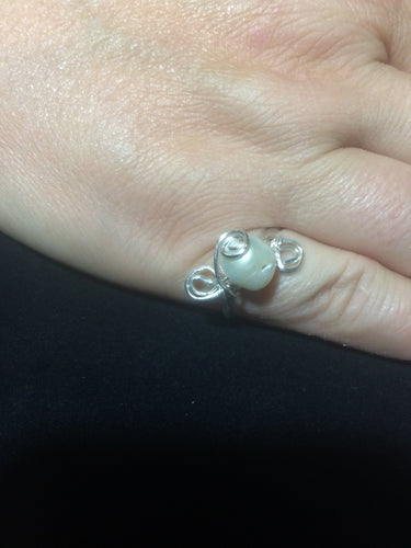 A cultured freshwater pearl sits atop oppositional swirls in fine silver, with a central spiral at the center. Rings made by this wire wrapping method vary individually. This one is approxmately a size 6, but may fit a slightly larger finger depending on how snug a fit you prefer.